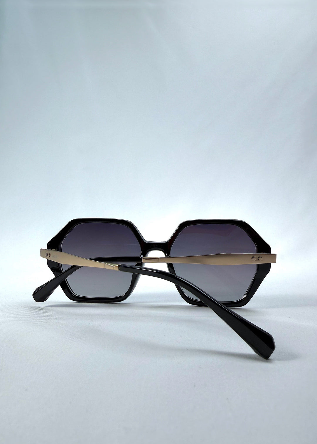 Folded back view of Ciel Arc sunglasses in Duskgold, featuring black and gold frame with dark lenses, showing the folded temples and back structure. 