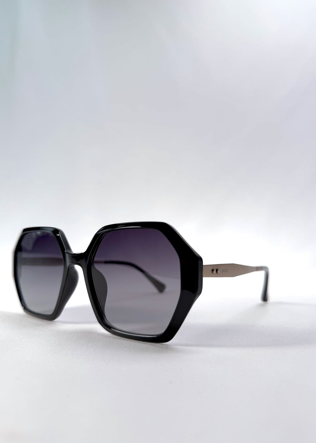Three-quarter front view of Ciel Arc sunglasses in Duskgold, featuring black and gold frame with dark lenses, showing the front shape and temple profile. 