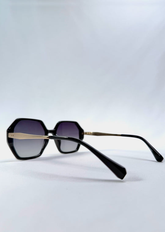 Side-angle view of Ciel Arc sunglasses in Duskgold, featuring black and gold frame with dark lenses, showing the lens shape and side temple profile. 