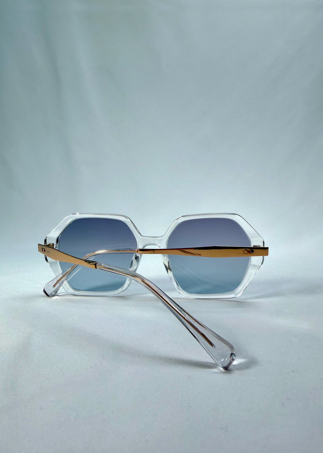 Folded back view of Ciel Arc sunglasses in Glacial Blue, featuring clear frame with blue gradient lenses, showing the folded temples and back structure.