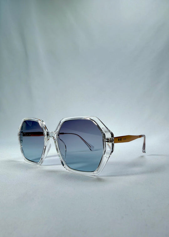 Three-quarter front view of Ciel Arc sunglasses in Glacial Blue, featuring clear frame with blue gradient lenses, showing the front shape and temple profile.