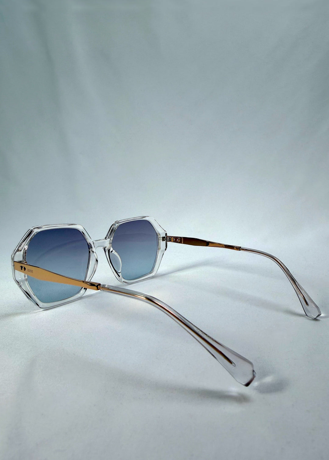 Side-angle view of Ciel Arc sunglasses in Glacial Blue, featuring clear frame with blue gradient lenses, showing the lens shape and side temple profile. 