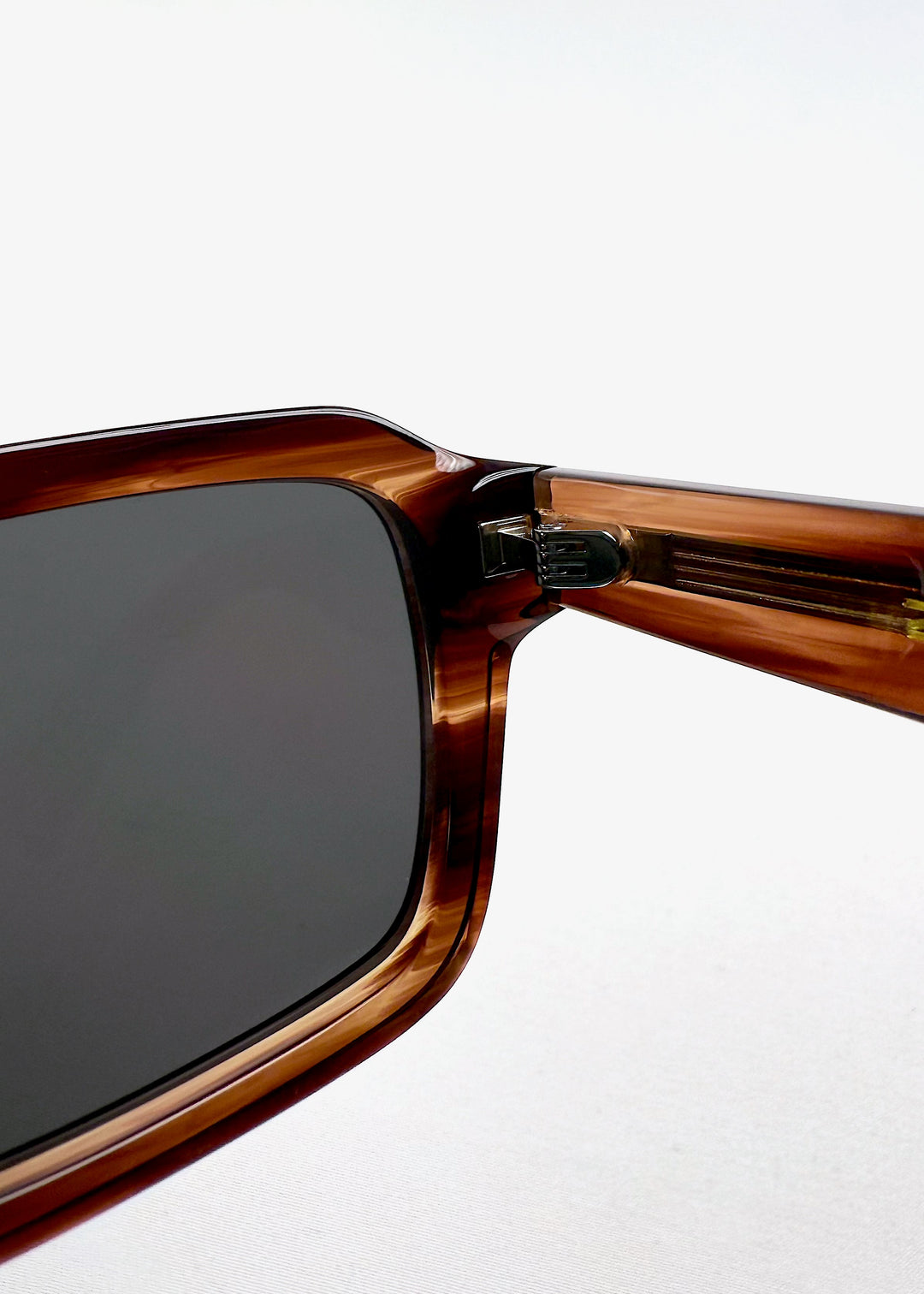 Close-up of inner hinge and arm of Crest sunglasses in Chestnut Marble, revealing inner engraving. 