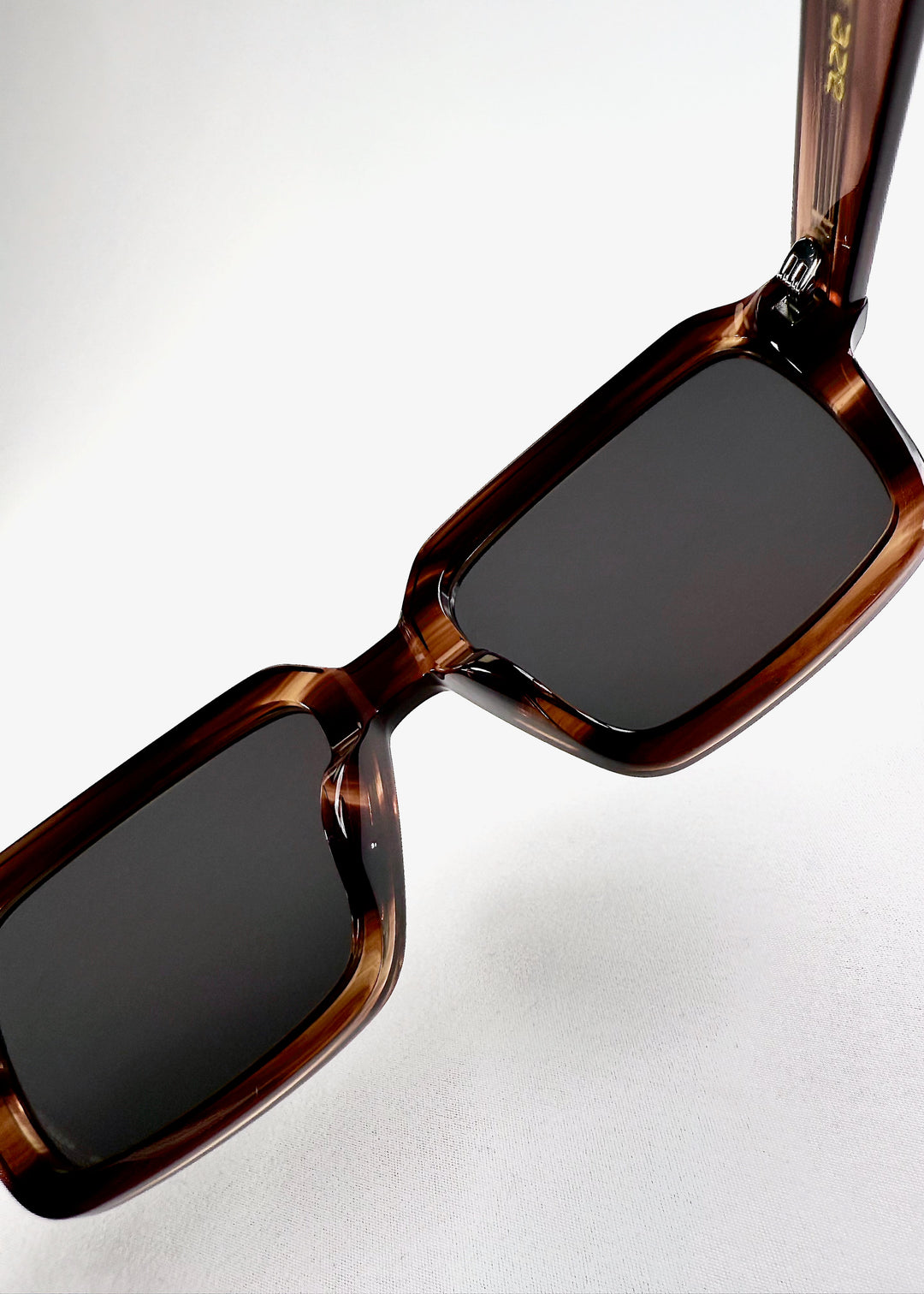 Close-up of the hinge and lens corner of Crest in Chestnut Marble, showcasing the smooth blend of form and function in its sculpted acetate design. 