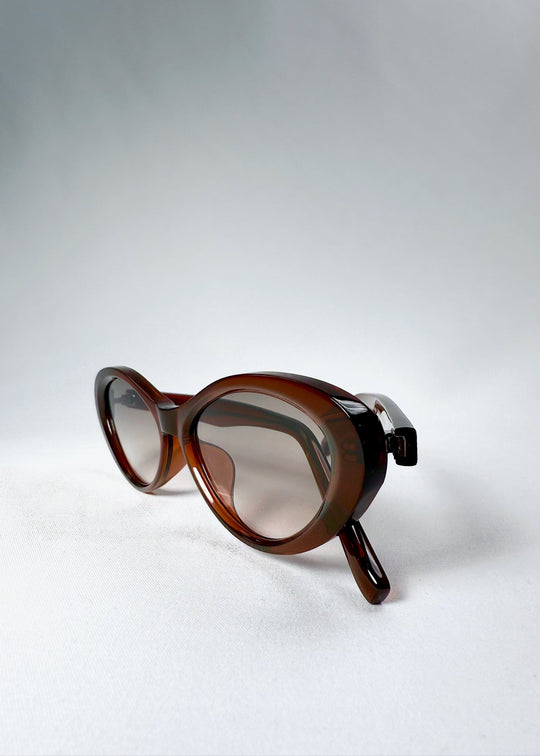 Three-quarter view of Dagger sunglasses in Crimson Mist with the temples folded behind the lenses. 