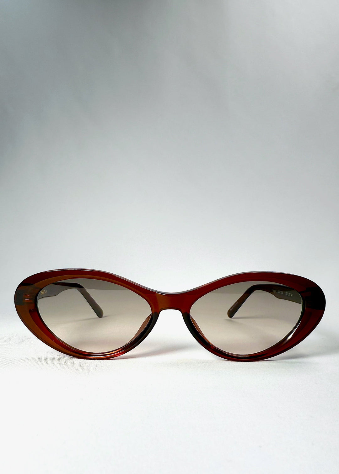 Front view of Dagger sunglasses in Crimson Mist showing the dark red cat-eye frame and lightly tinted lenses. 