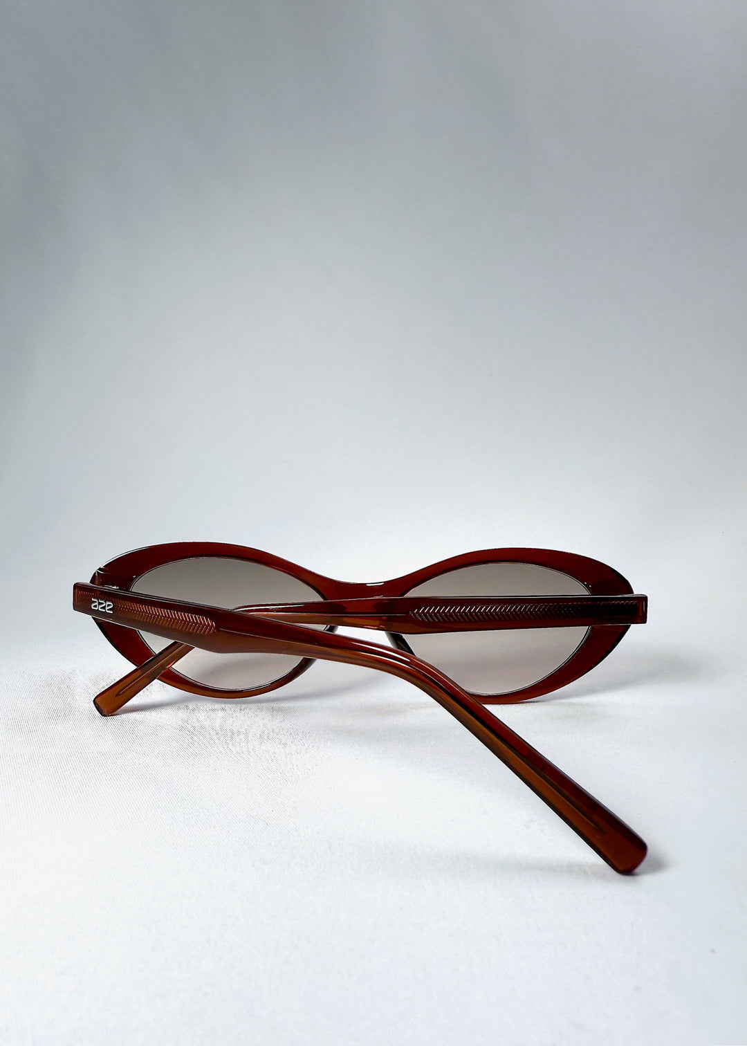 Rear folded view of Dagger sunglasses in Crimson Mist showing the crossed temples and AZE logo. 