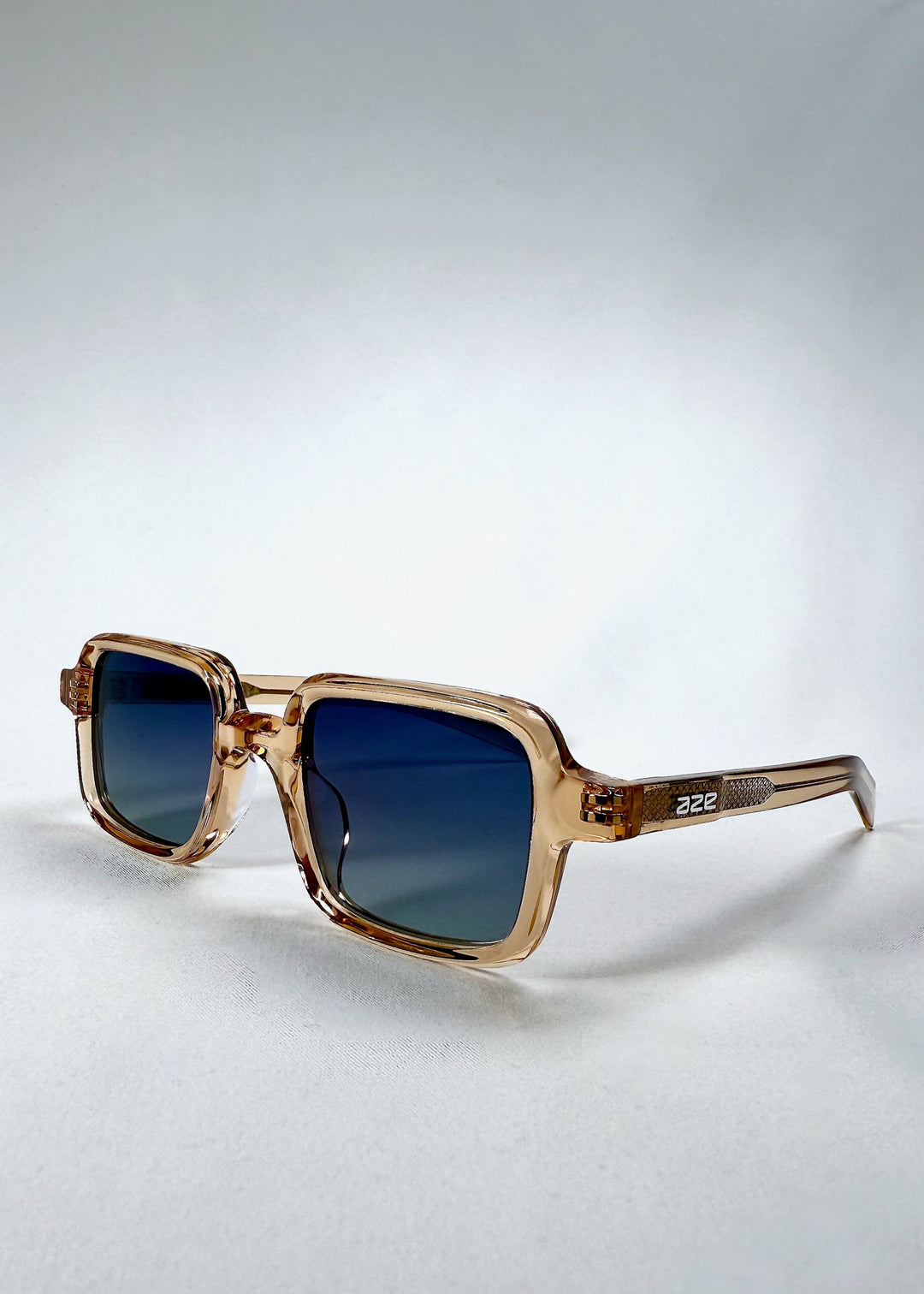 Angled front view of Draxen - Amber Frost sunglasses showing soft brown acetate frame and Aze logo on the temple. 