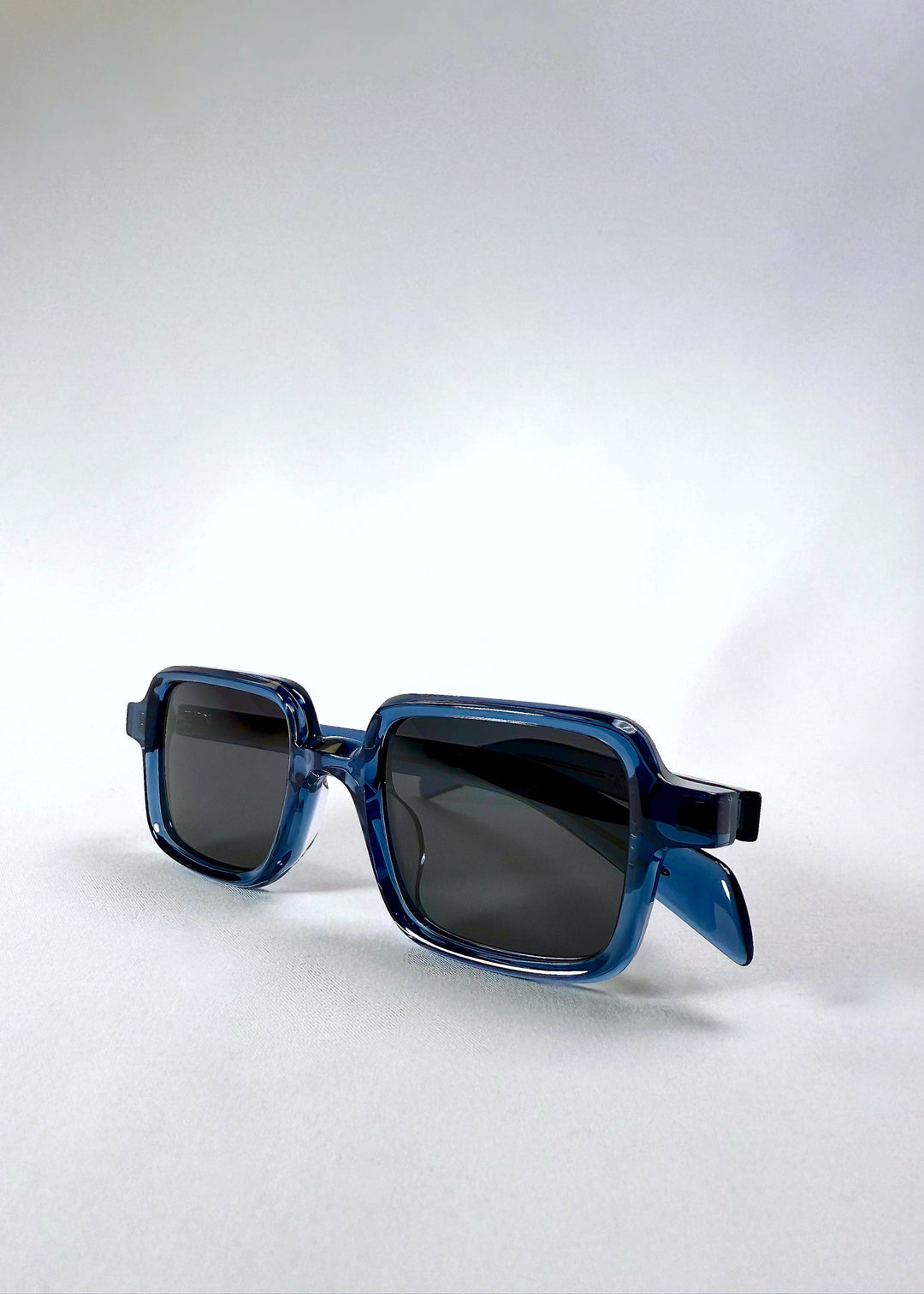 Angled detail view of Draxen in Glacial Blue, highlighting the transparent acetate frame and rectangular lens shape. 