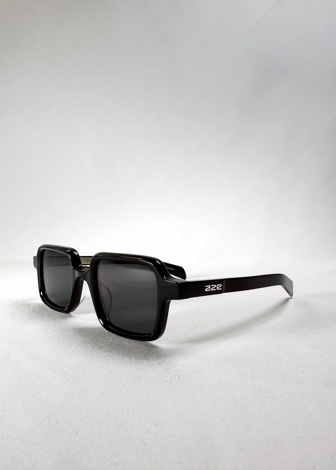 Front angle view of Draxen sunglasses in Obsidian Black showing the Aze logo on the temple and the compact silhouette. 
