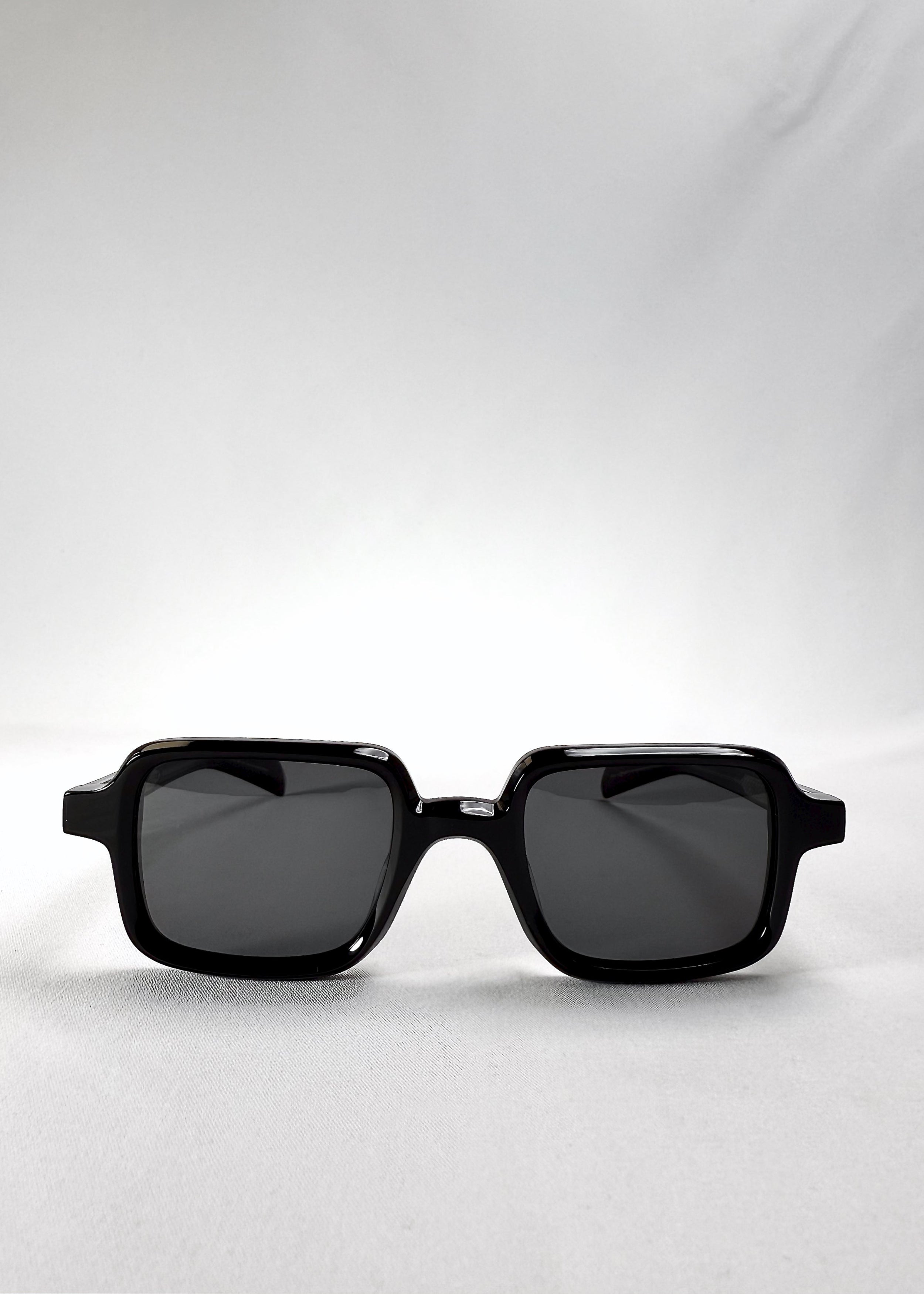 Front view of Draxen sunglasses in Obsidian Black, featuring a petite rectangular acetate frame and dark polarized lenses.