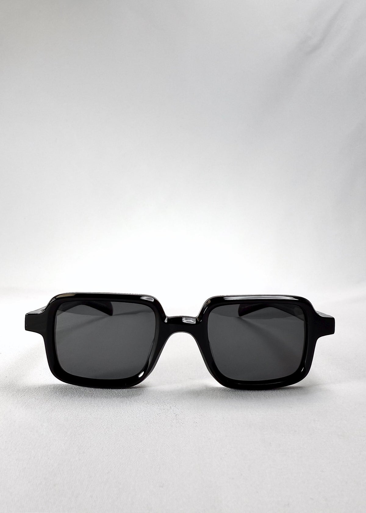 Front view of Draxen sunglasses in Obsidian Black, featuring a petite rectangular acetate frame and dark polarized lenses.