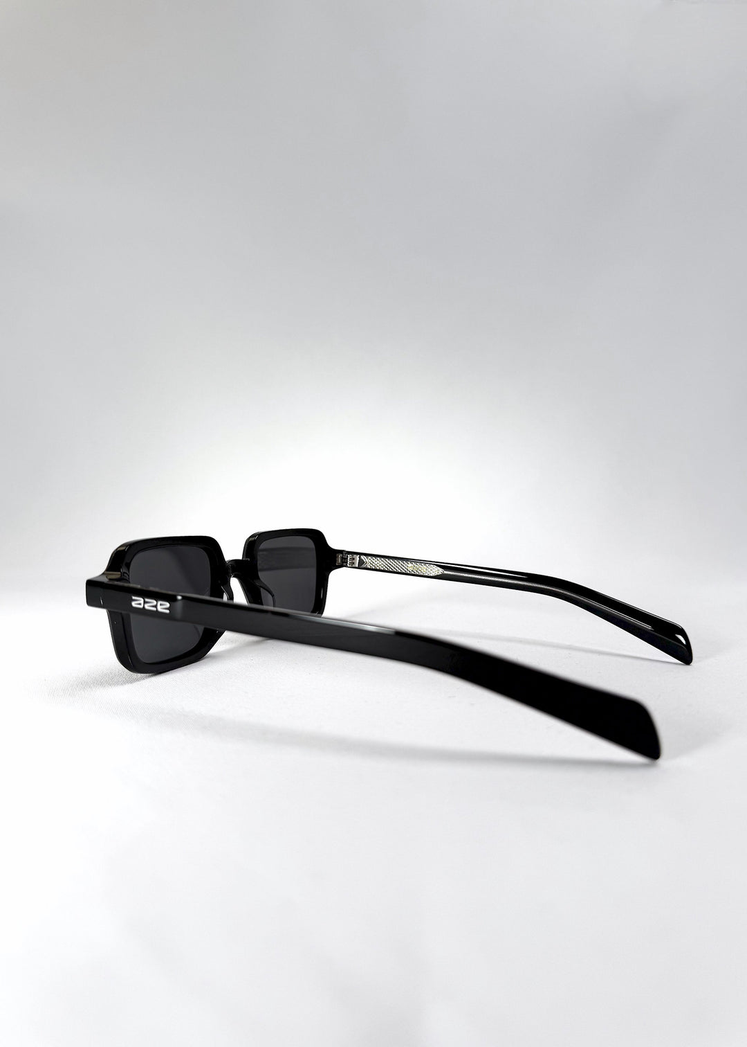 Side temple view of Draxen sunglasses in Obsidian Black, showcasing the slender acetate arms and engraved hinge detail. 