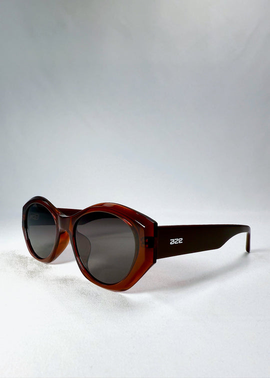 Eclipse Feline sunglasses in Burnished Umber shown from a front angle, highlighting the bold red-brown translucent frame and smoky HD nylon lenses. 