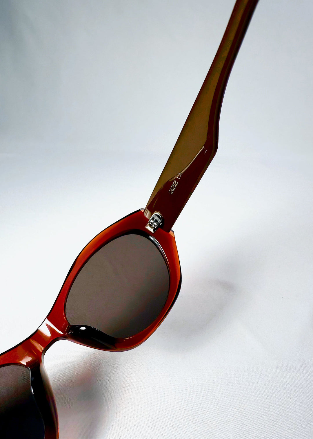 Inside view of Eclipse Feline sunglasses, highlighting interior temple branding and red-brown acetate tone. 