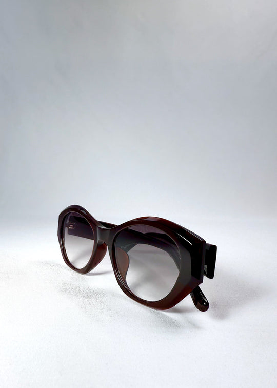 Angled shot highlighting the bold cat-eye frame and HD nylon gradient lenses of Eclipse Feline in Crimson Mirage.
