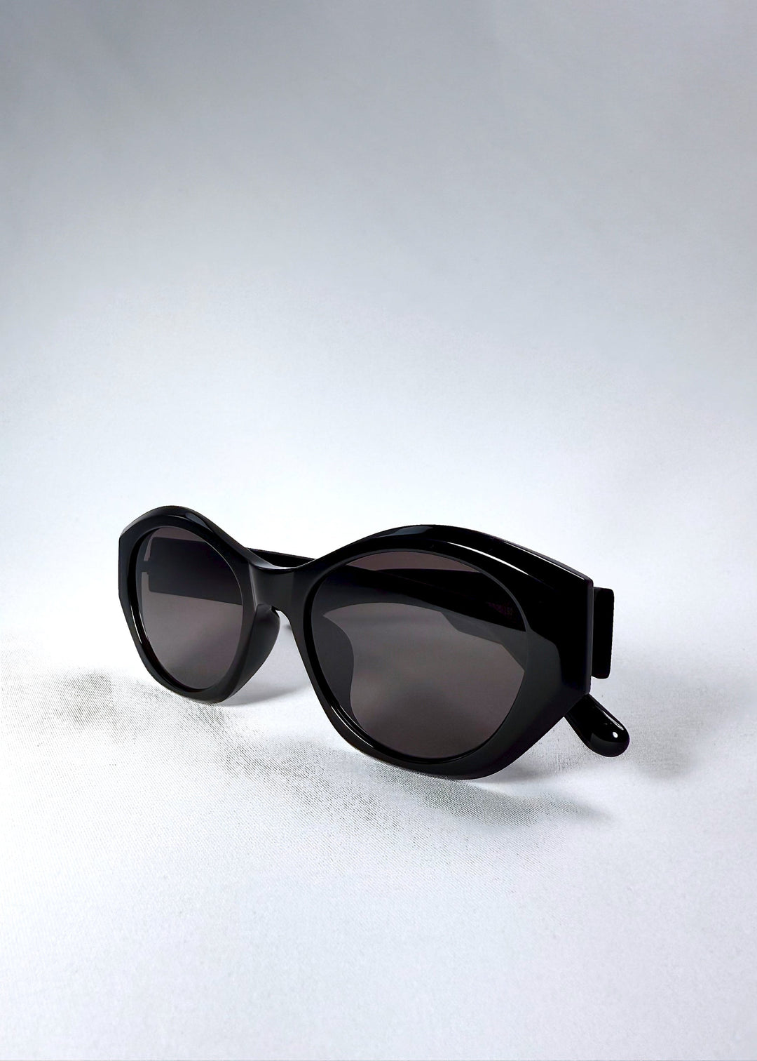 Frame angle detail of Eclipse Feline sunglasses showing the sculpted edges and glossy black finish. 