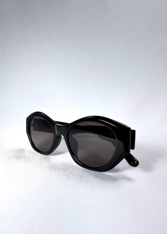 Frame angle detail of Eclipse Feline sunglasses showing the sculpted edges and glossy black finish. 