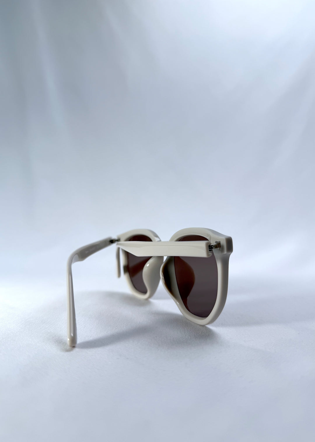Back-angle view of Elara sunglasses in Creamy Beige, featuring creamy beige acetate frame and warm brown lenses, showing the back structure and temple alignment.