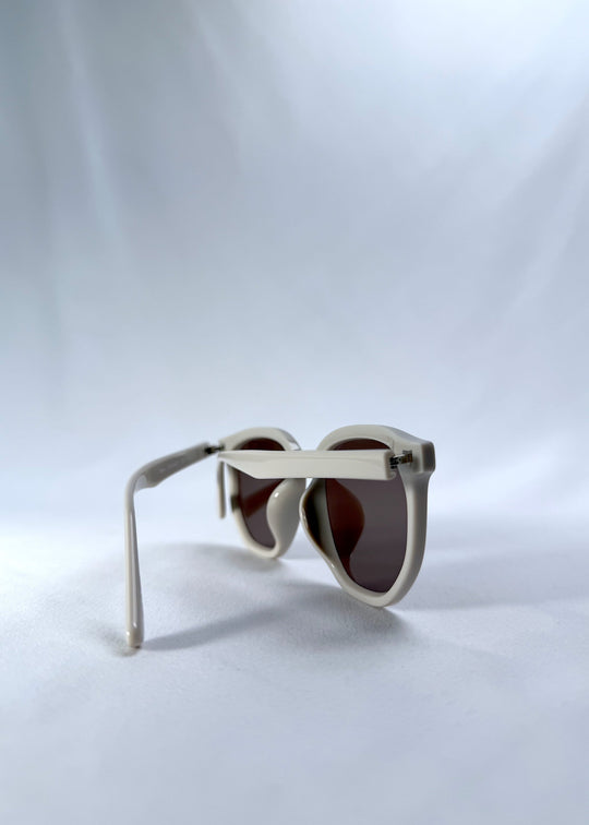 Back-angle view of Elara sunglasses in Creamy Beige, featuring creamy beige acetate frame and warm brown lenses, showing the back structure and temple alignment. 