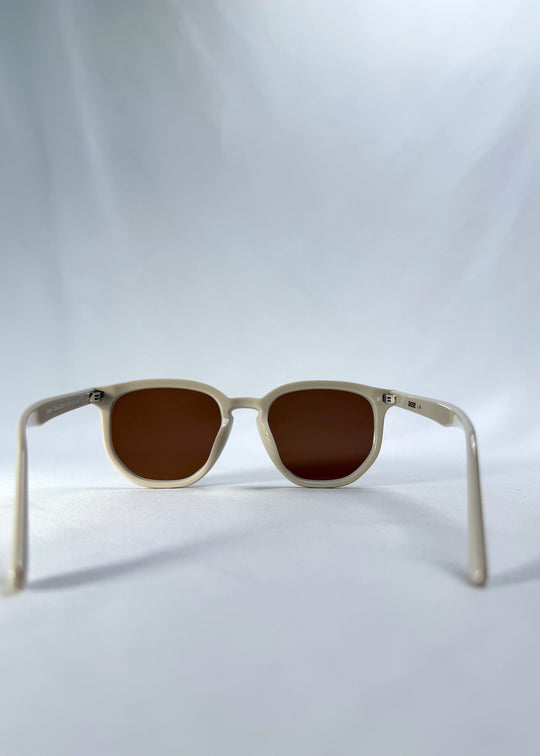 Back view of Elara sunglasses in Creamy Beige, featuring creamy beige acetate frame and warm brown lenses, showing the inside frame and open temples. 