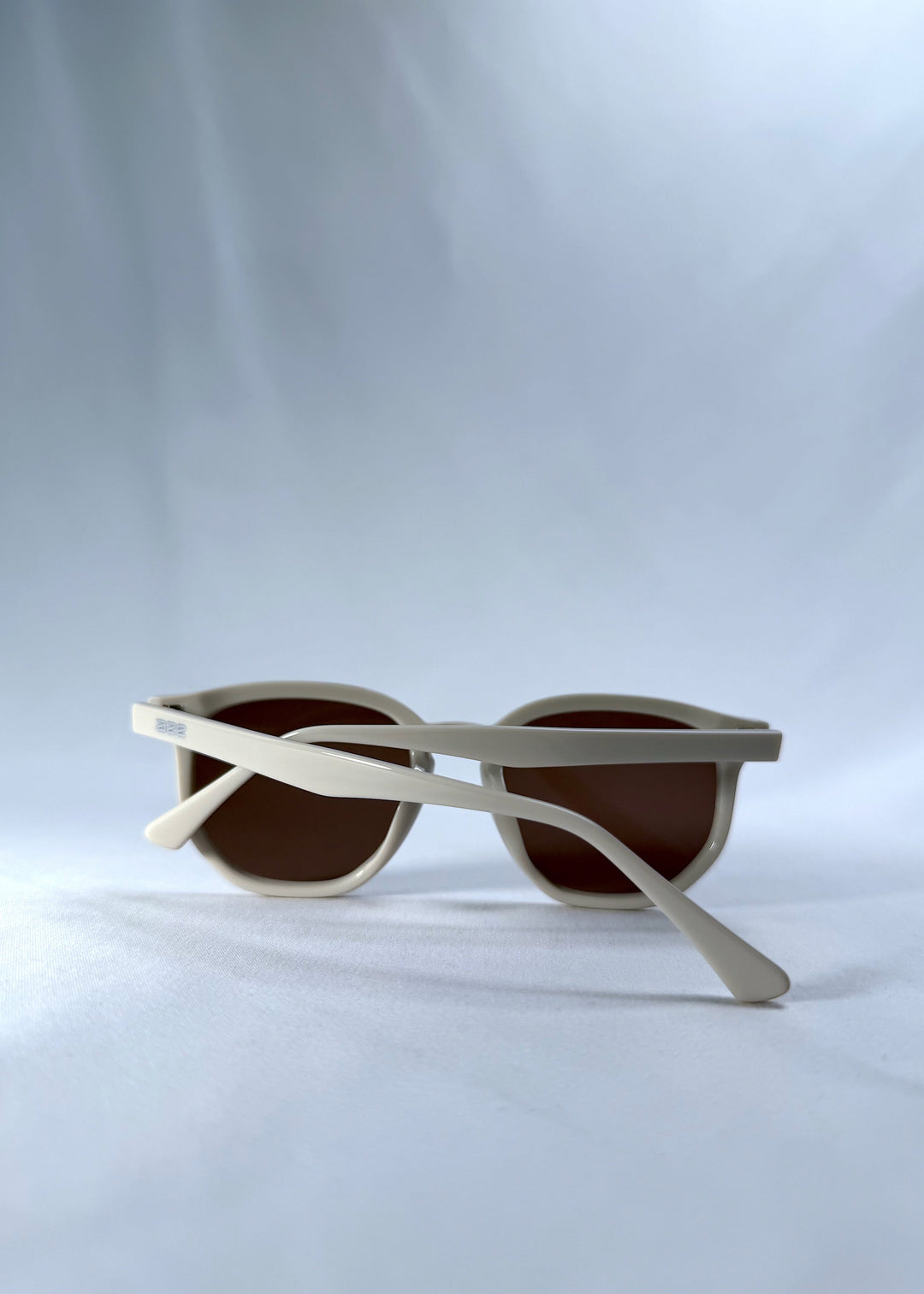 Folded view of Elara sunglasses in Creamy Beige, featuring creamy beige acetate frame and warm brown lenses, showing the folded temples and frame profile. 