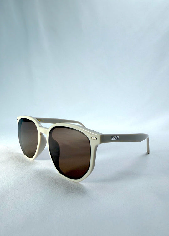 Three-quarter front view of Elara sunglasses in Creamy Beige, featuring creamy beige acetate frame and warm brown lenses, showing the front shape and temple profile. 