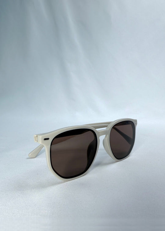 Side-angle view of Elara sunglasses in Creamy Beige, featuring creamy beige acetate frame and warm brown lenses, showing the lens shape and side temple profile. 