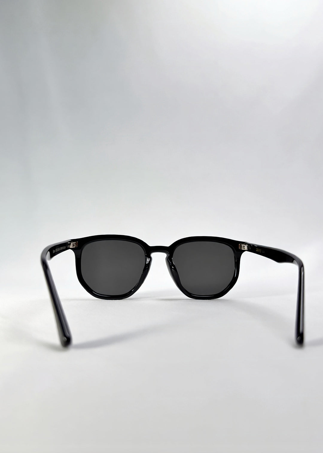 Back view of Elara sunglasses in Obsidian Black, featuring black acetate frame and dark lenses, showing the inside frame and open temples. 