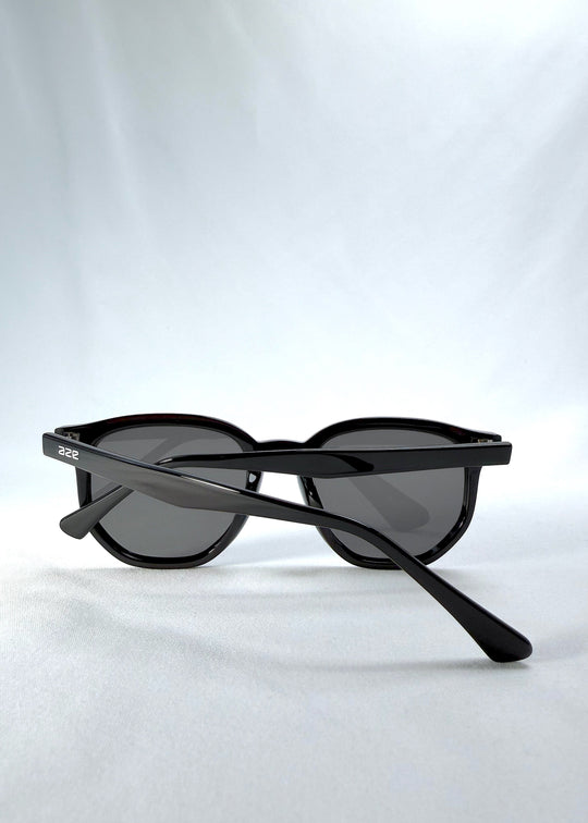 Folded view of Elara sunglasses in Obsidian Black, featuring black acetate frame and dark lenses, showing the folded temples and frame profile. 