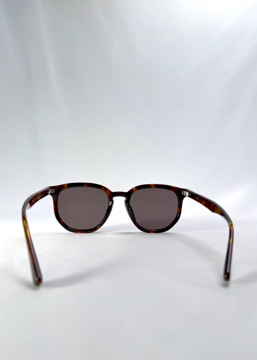 Back view of Elara sunglasses in Tortoiseshell, featuring tortoiseshell acetate frame and dark lenses, showing the inside frame and open temples. 