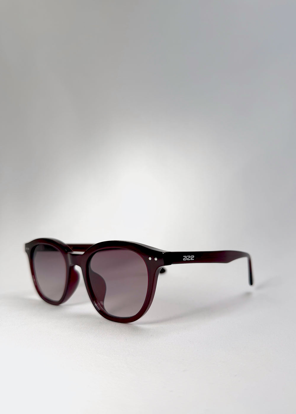 Front angle view of Elvor sunglasses in Mulberry Mist, showing soft violet-to-grey gradient lenses and a rounded frame silhouette.