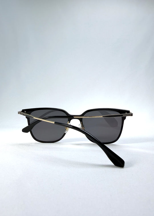 Folded view of Eon Drift sunglasses in Duskgold, featuring a structured black frame, gold-tone accents, and smoky lenses, showing the folded temples and frame profile.