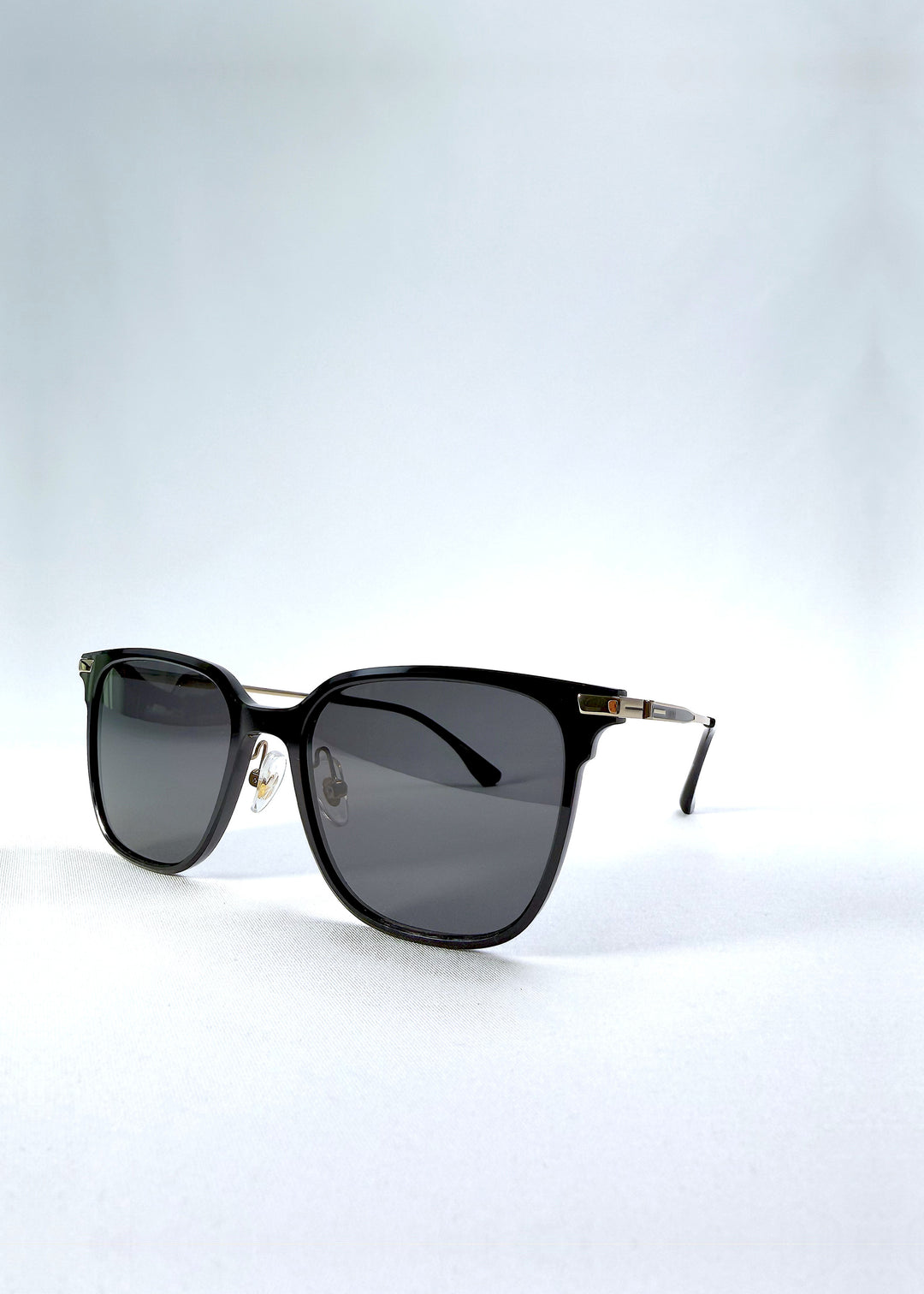 Three-quarter front view of Eon Drift sunglasses in Duskgold, featuring a structured black frame, gold-tone accents, and smoky lenses, showing the frame shape and temple profile.