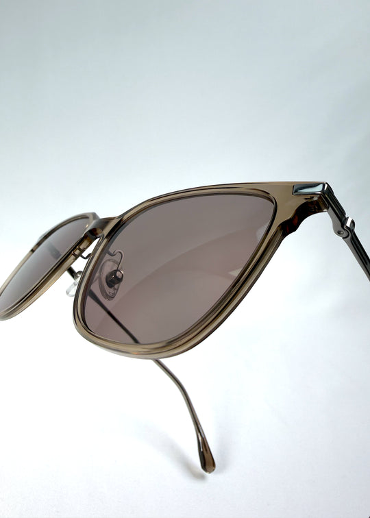 Close-up hinge detail view of Eon Drift sunglasses in Mocha Bronze, featuring a warm mocha frame, bronze-tone accents, and brown gradient lenses, showing the hinge construction, lens edge, and temple connection.
