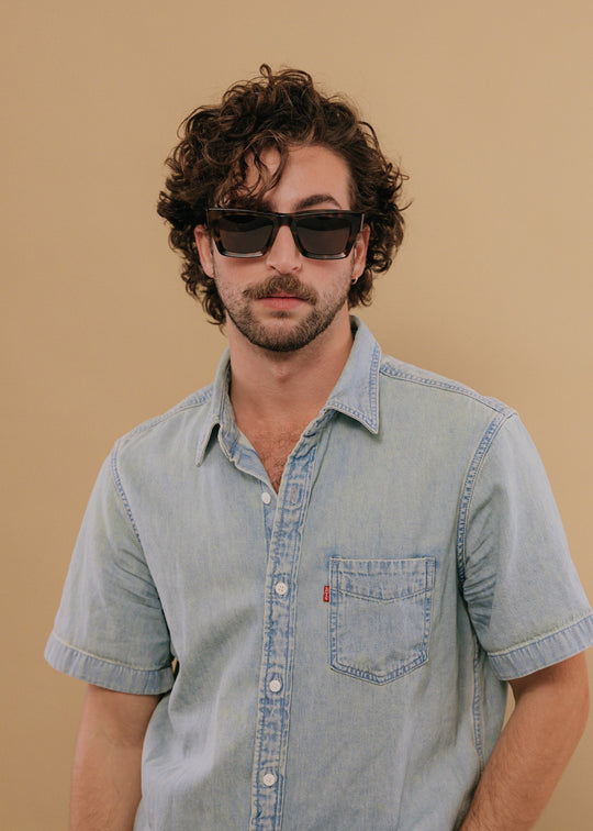 Male model wearing Fomalhaut tortoiseshell acetate prescription sunglasses, styled in a casual outfit. 
