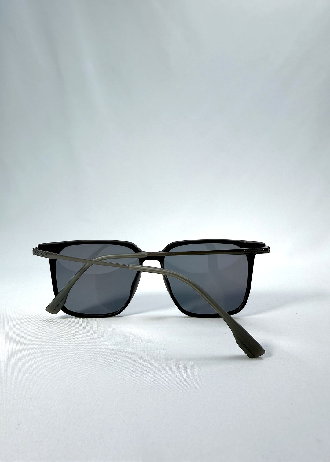 Folded view of Gemini sunglasses in Matte Black, featuring light titanium frame, squared lens shape, and polarized lenses, showing the folded temples and frame profile.