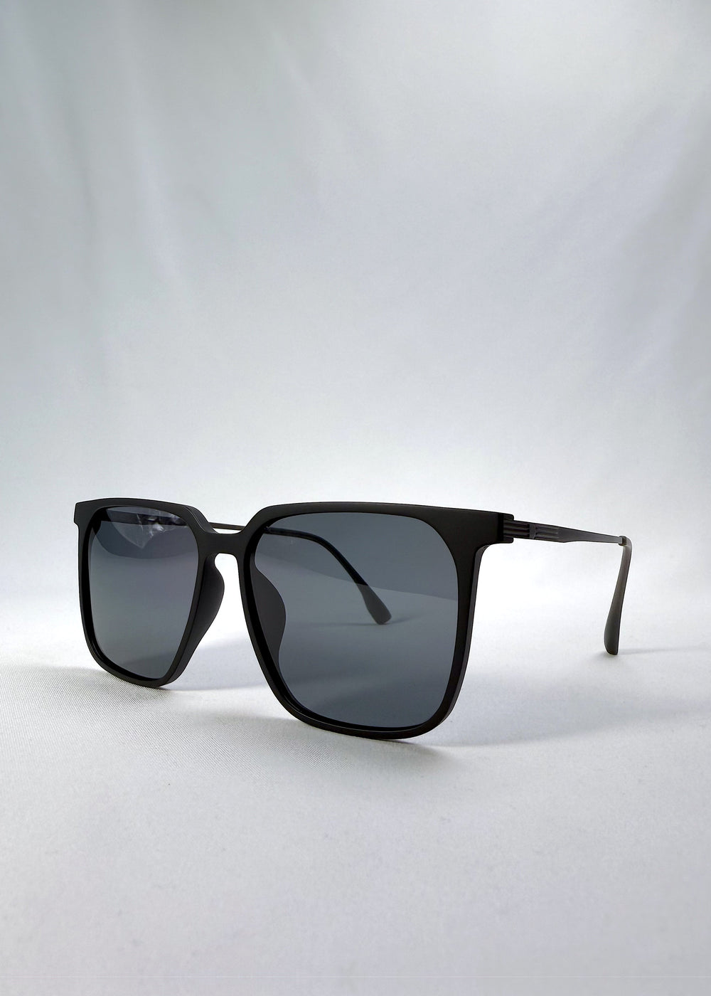 Three-quarter front view of Gemini sunglasses in Matte Black, featuring light titanium frame, squared lens shape, and polarized lenses, showing the front shape and temple profile.