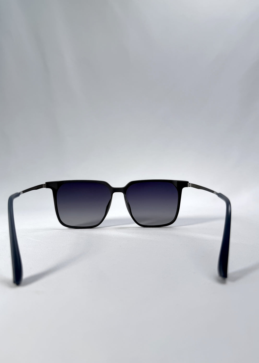 Back view of Gemini sunglasses in Matte Blue, featuring light titanium frame, squared lens shape, and polarized lenses, showing the inside frame and open temples.