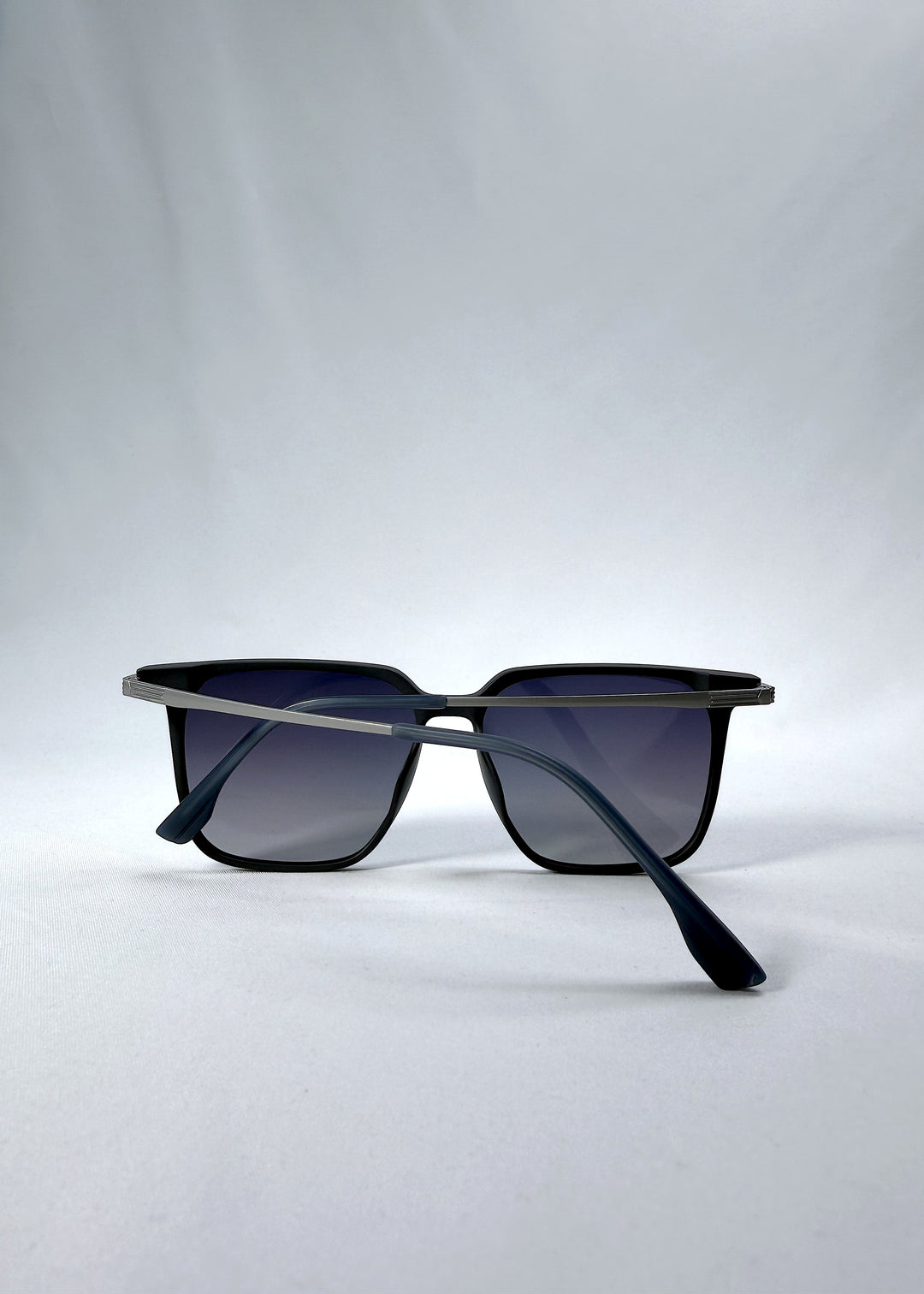 Folded view of Gemini sunglasses in Matte Blue, featuring light titanium frame, squared lens shape, and polarized lenses, showing the folded temples and frame profile.