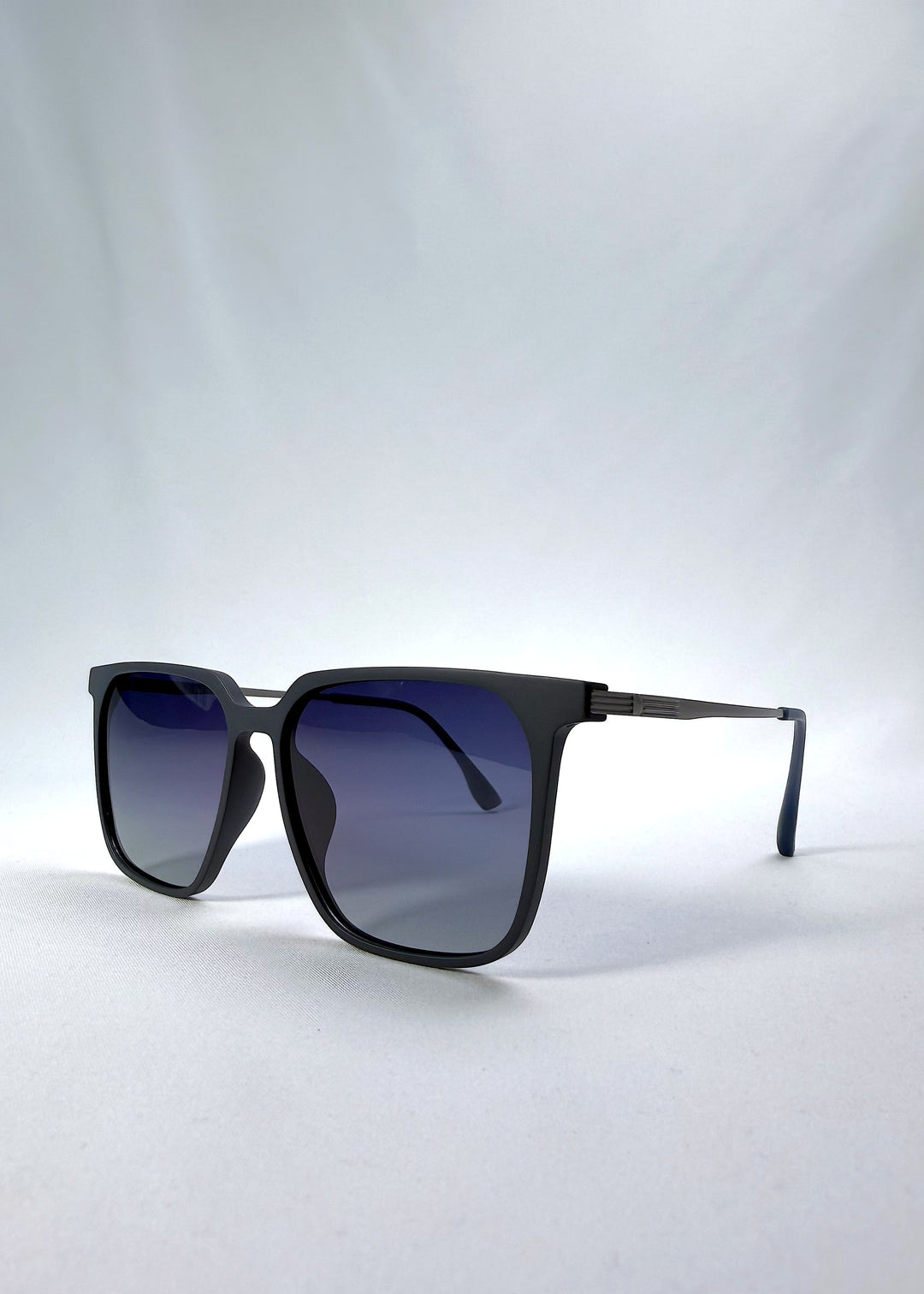 Three-quarter front view of Gemini sunglasses in Matte Blue, featuring light titanium frame, squared lens shape, and polarized lenses, showing the front shape and temple profile.