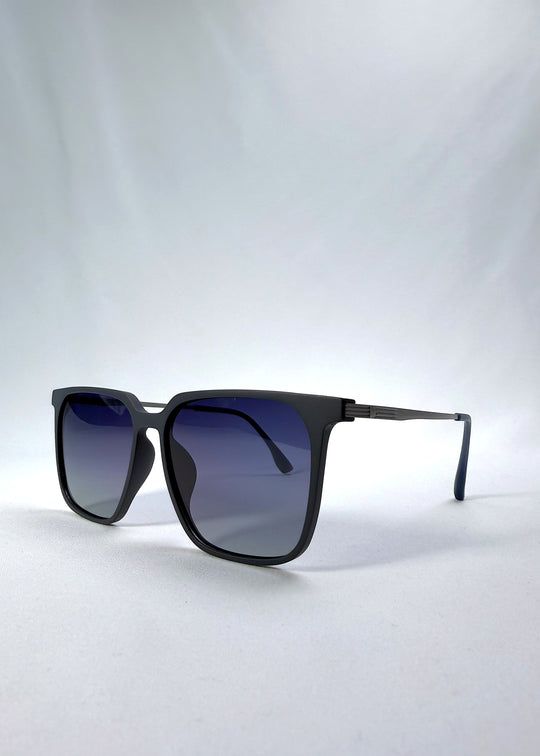 Three-quarter front view of Gemini sunglasses in Matte Blue, featuring light titanium frame, squared lens shape, and polarized lenses, showing the front shape and temple profile.