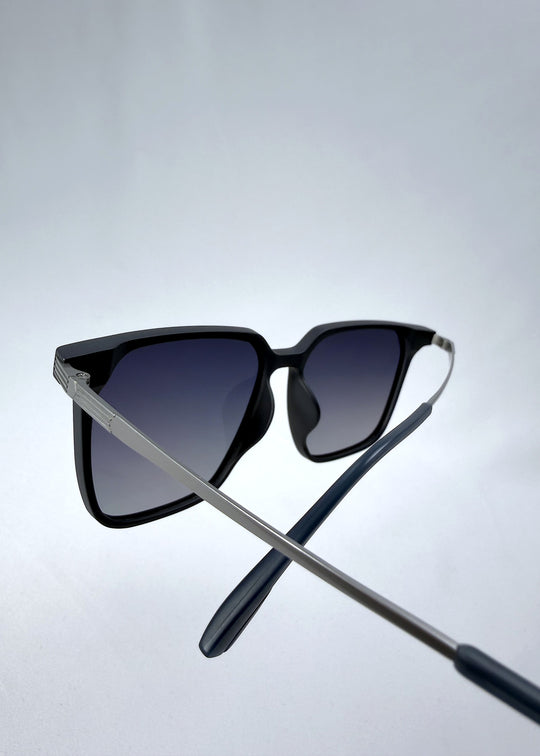 Close-up temple detail view of Gemini sunglasses in Matte Blue, featuring light titanium frame, squared lens shape, and polarized lenses, showing the temple arm and hinge area.