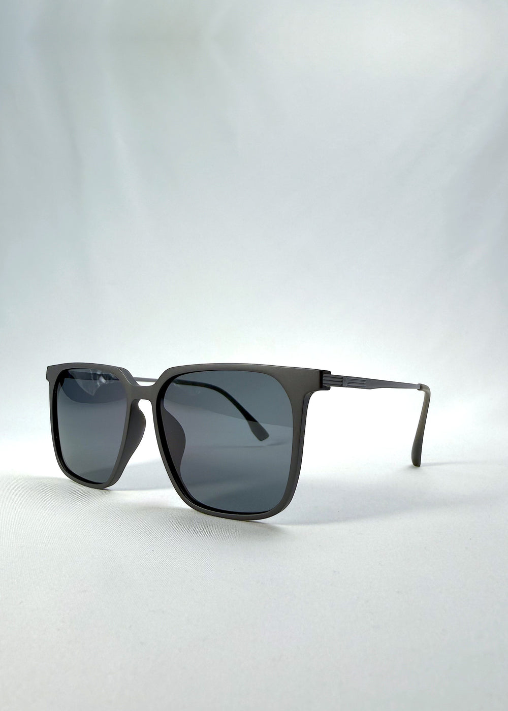 Three-quarter front view of Gemini sunglasses in Matte Gray, featuring light titanium frame, squared lens shape, and polarized lenses, showing the front shape and temple profile.