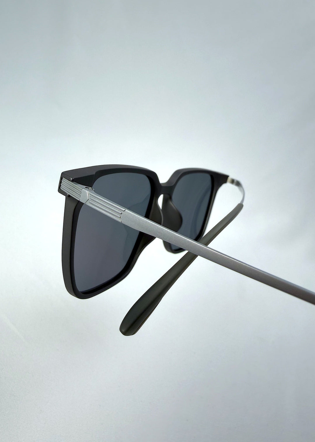 Close-up temple detail view of Gemini sunglasses in Matte Gray, featuring light titanium frame, squared lens shape, and polarized lenses, showing the temple arm and hinge area.