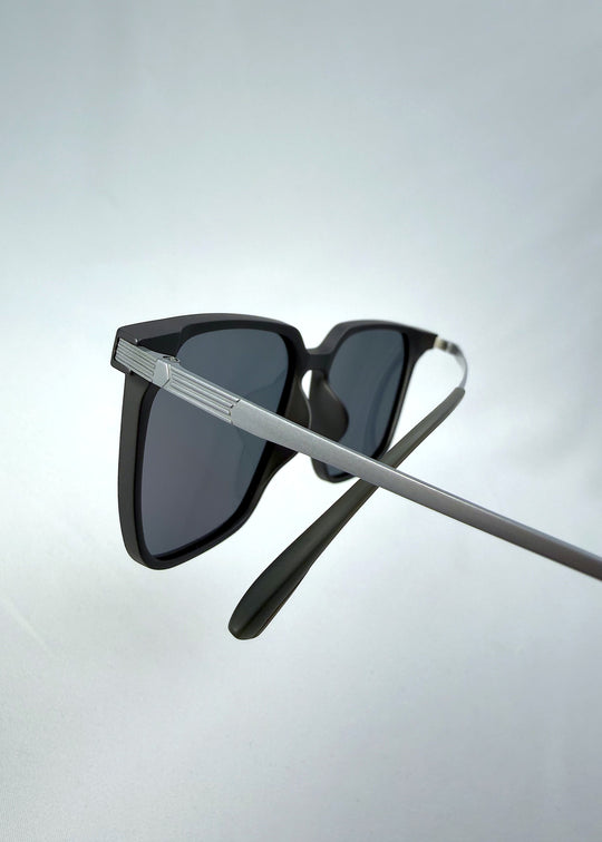 Close-up temple detail view of Gemini sunglasses in Matte Gray, featuring light titanium frame, squared lens shape, and polarized lenses, showing the temple arm and hinge area.