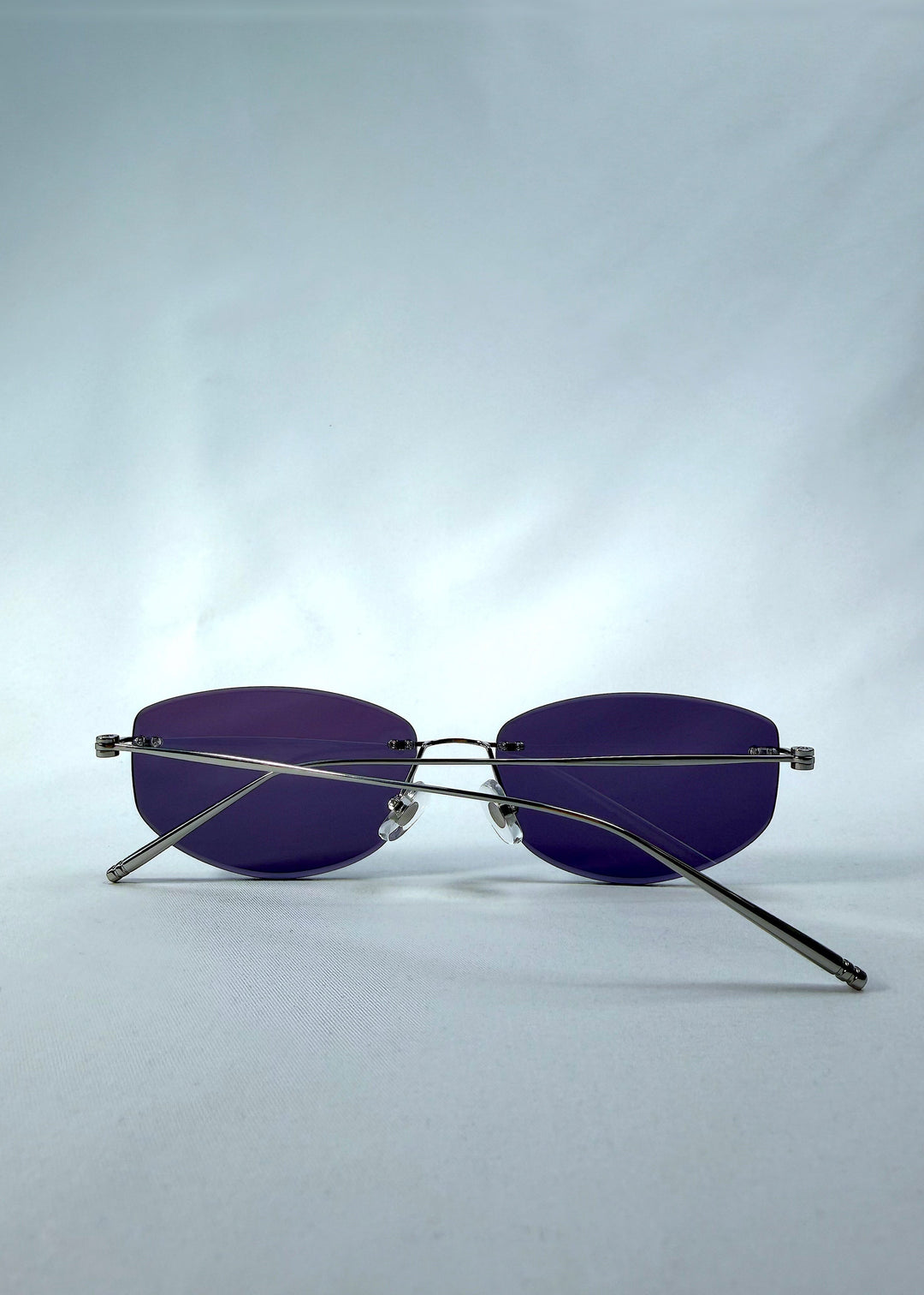 Folded back view of Halo Trace sunglasses in Glacial Blue, featuring blue-grey nylon lenses and a lightweight titanium frame, showing the folded temples and back structure. 
