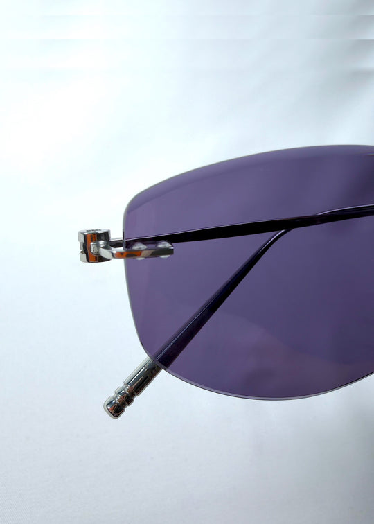 Close-up hinge detail view of Halo Trace sunglasses in Glacial Blue, featuring blue-grey nylon lenses and a lightweight titanium frame, showing the hinge, lens edge, and temple detail.