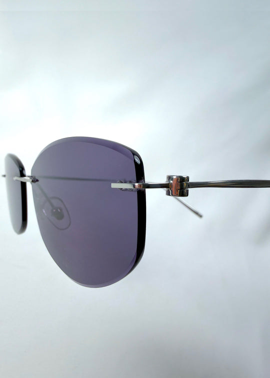 Close-up side detail view of Halo Trace sunglasses in Glacial Blue, featuring blue-grey nylon lenses and a lightweight titanium frame, showing the side lens edge, hinge, and temple detail.