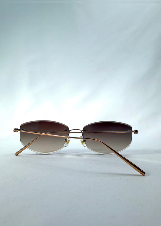 Folded back view of Halo Trace sunglasses in Verdant Halo, featuring green-to-rose gradient nylon lenses and a lightweight titanium frame, showing the folded temples and back structure. 
